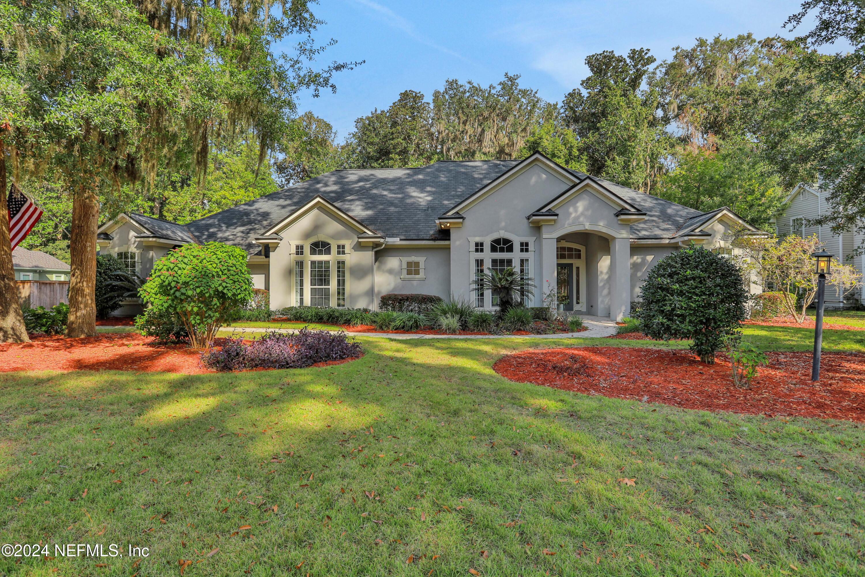 a view of a house with a big yard and large trees