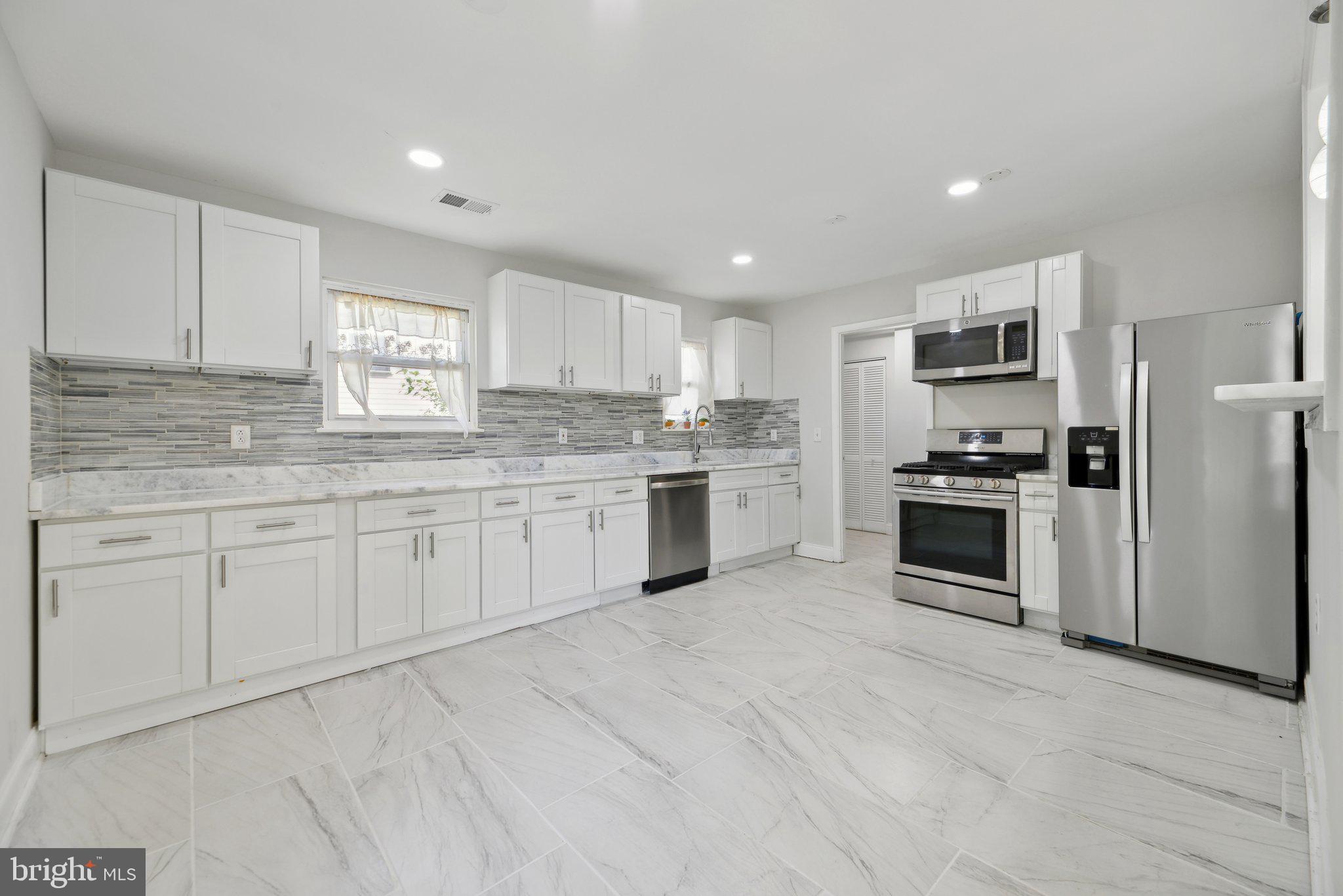 a kitchen with granite countertop white cabinets and stainless steel appliances