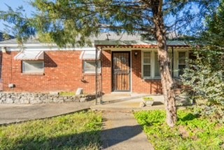 front view of a house with a yard and an trees