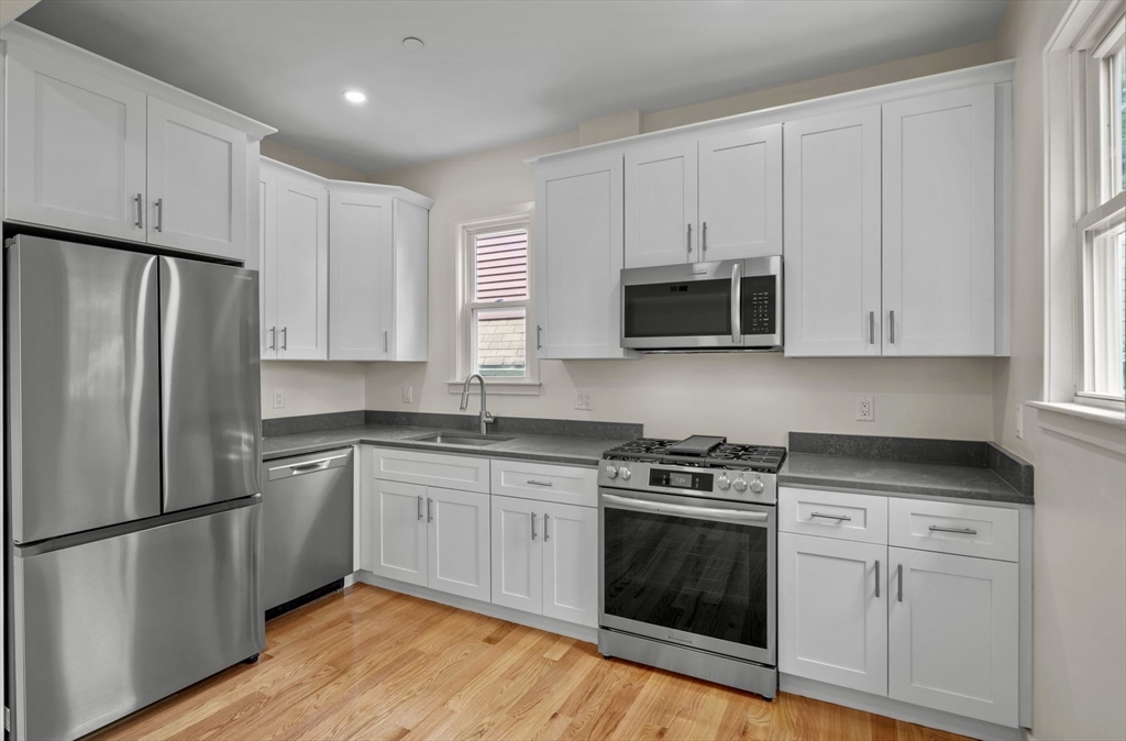 a kitchen with cabinets stainless steel appliances and a window