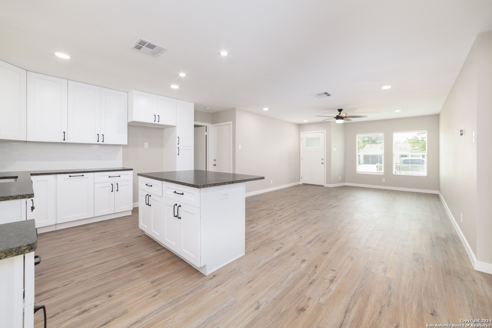 a kitchen with stainless steel appliances granite countertop a stove a sink and white cabinets with wooden floor