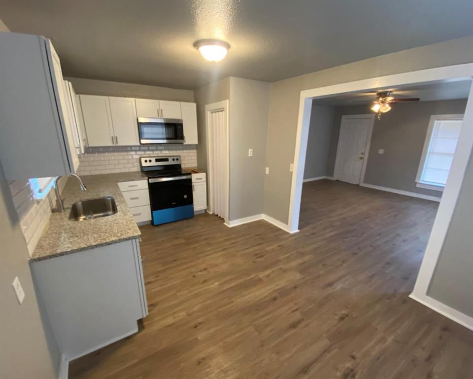 a kitchen with granite countertop a refrigerator stove and sink