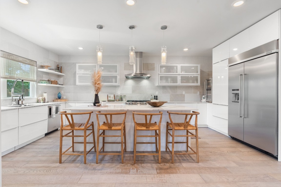 a kitchen with kitchen island a dining table chairs cabinets and wooden floor