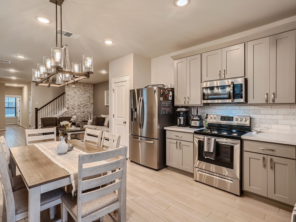 a kitchen with stainless steel appliances granite countertop a sink a stove a refrigerator cabinets and chairs