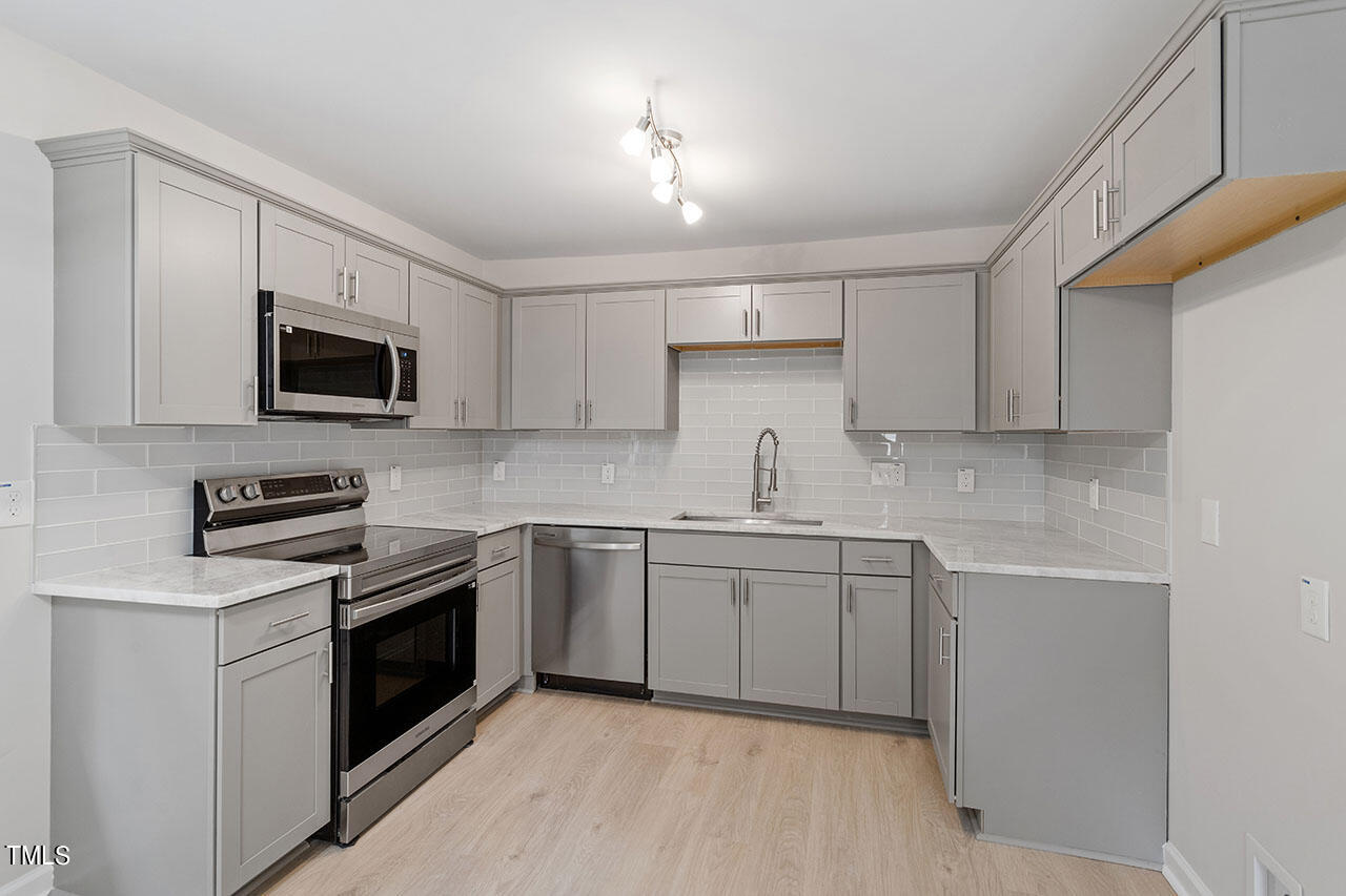 a kitchen with granite countertop white cabinets sink and stainless steel appliances