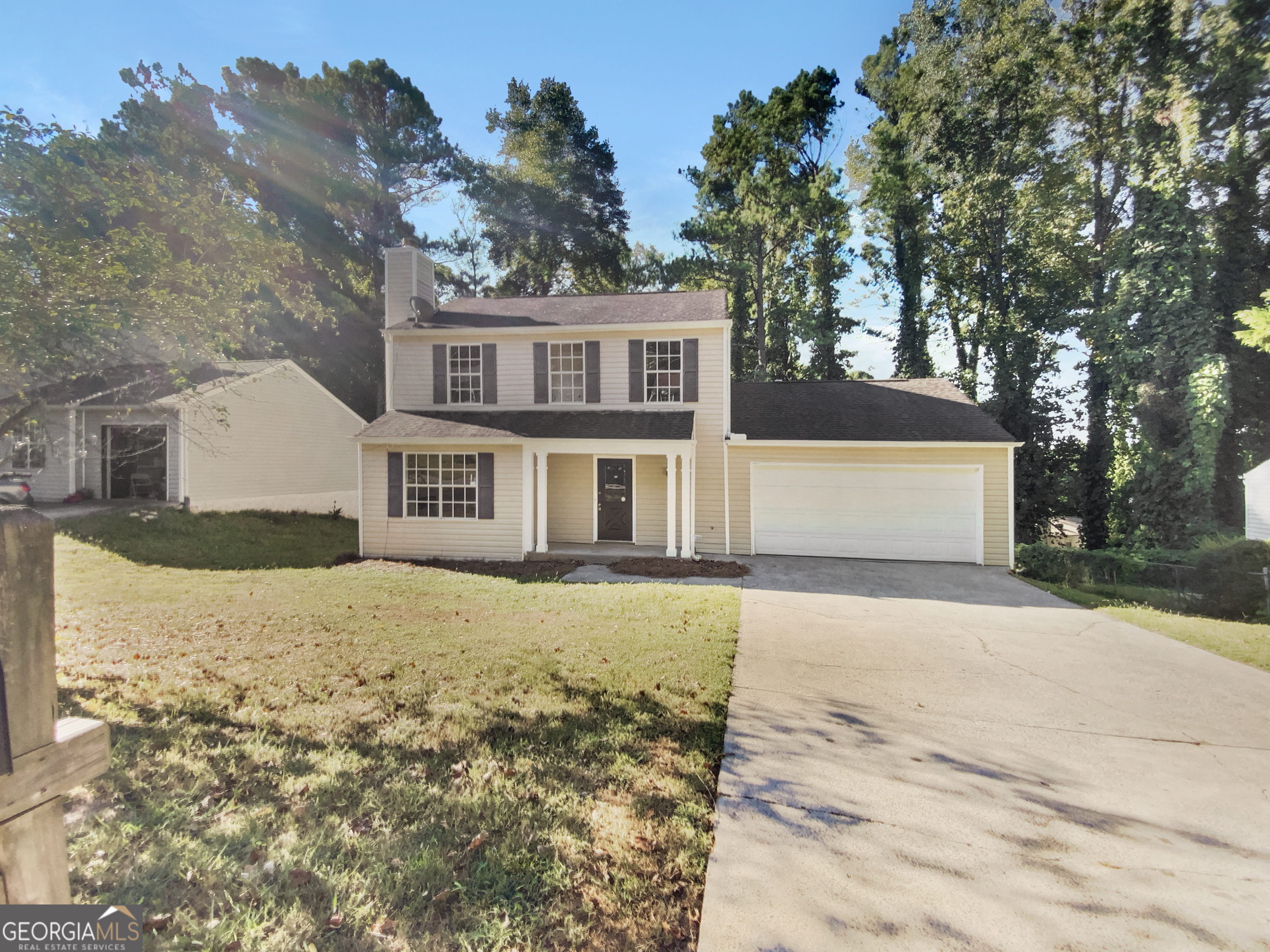 a front view of a house with a yard covered with trees