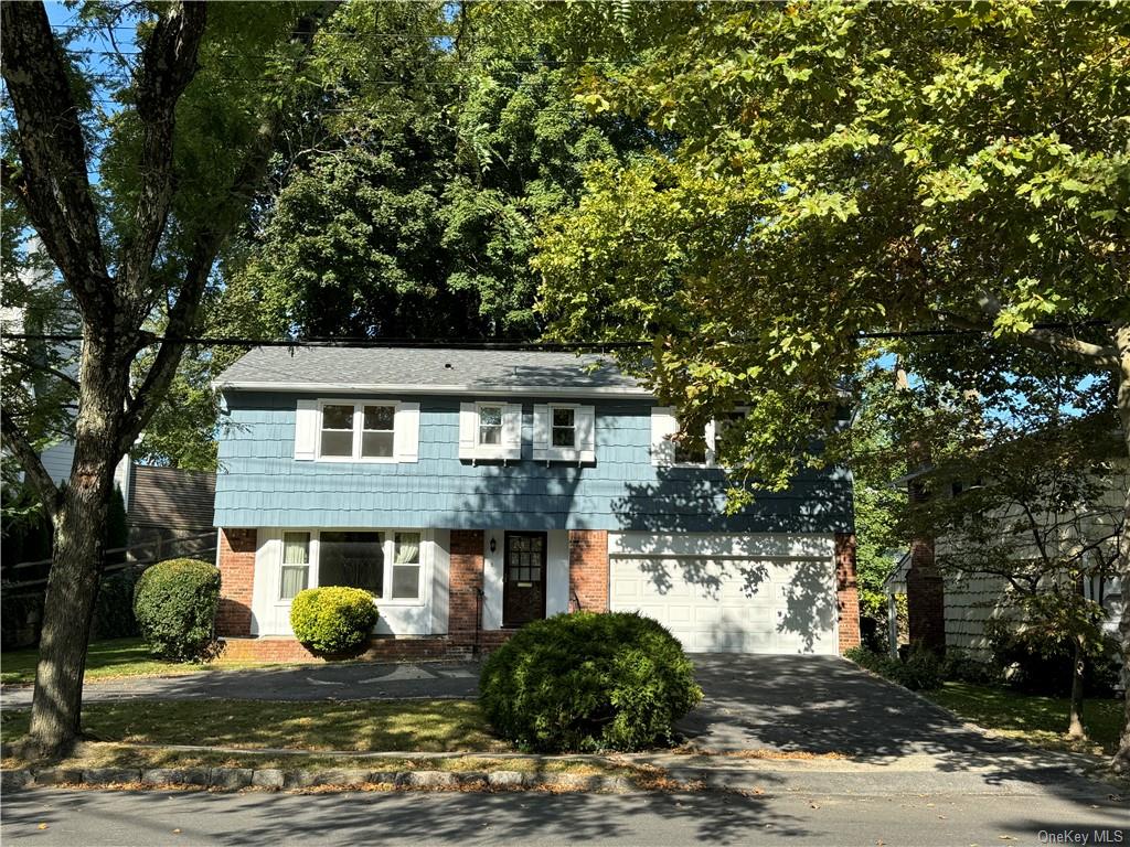 View of front of property featuring a 2-car garage and circular driveway