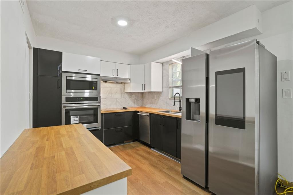 a kitchen with a refrigerator a stove top oven and cabinets