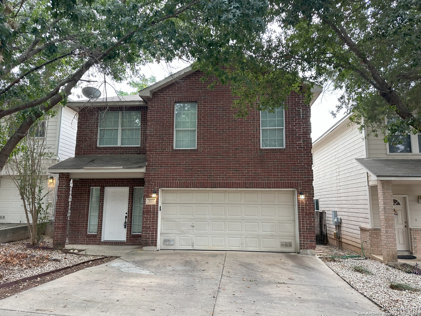 a front view of a house with a tree