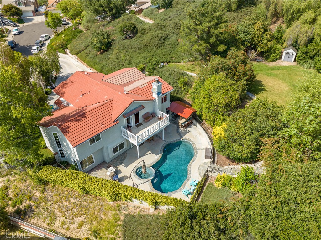 an aerial view of a house with swimming pool and large trees