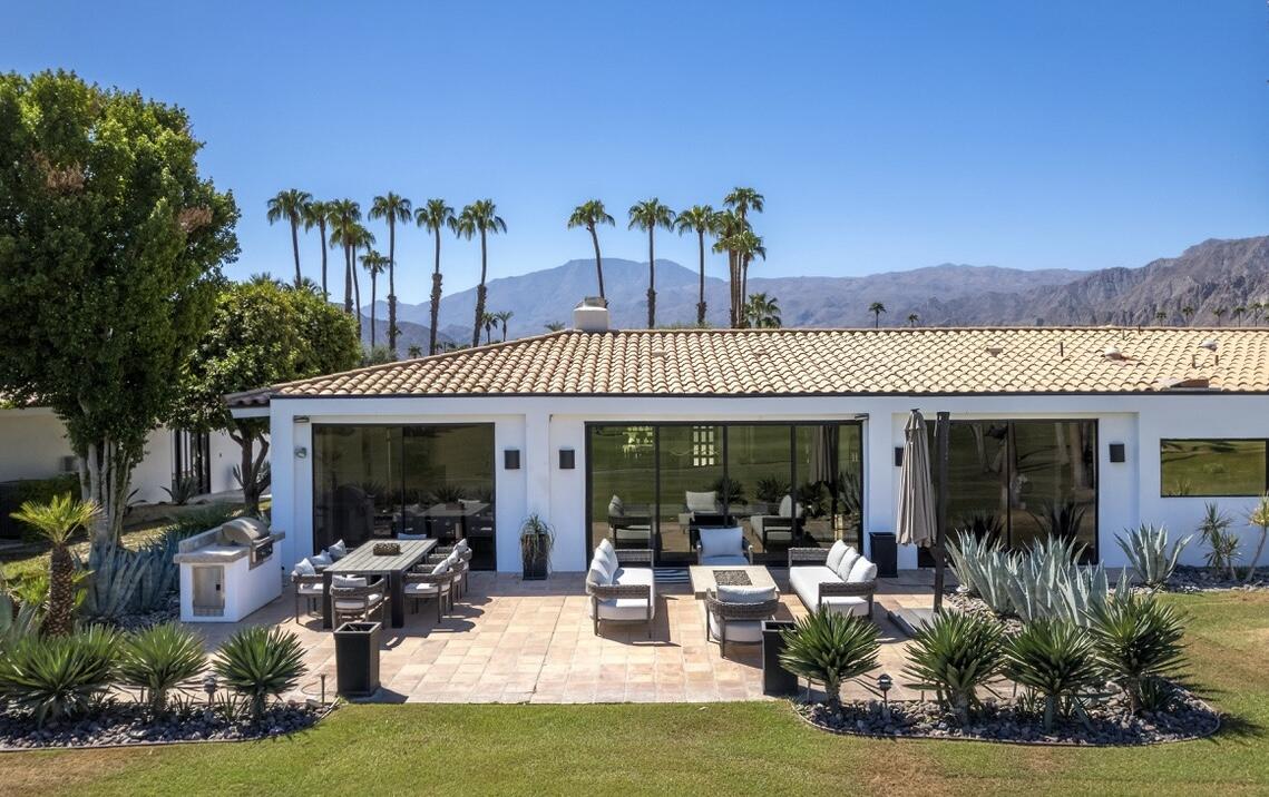 a view of a patio with table and chairs potted plants and a large tree