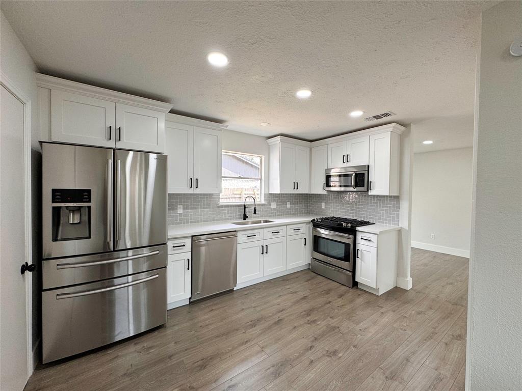 a kitchen with a refrigerator stainless steel appliances wooden floor and a window