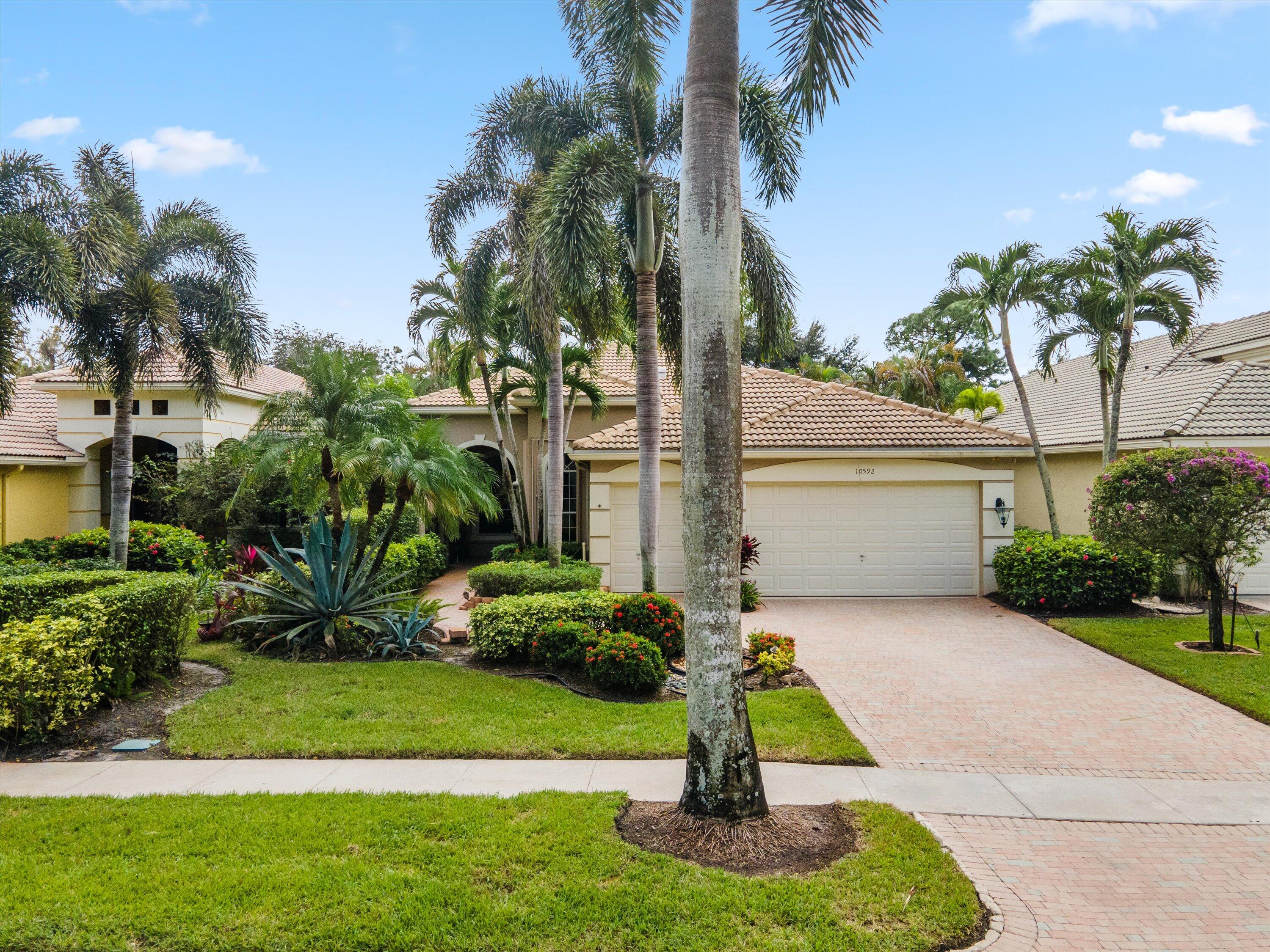 a front view of a house with a yard and palm trees