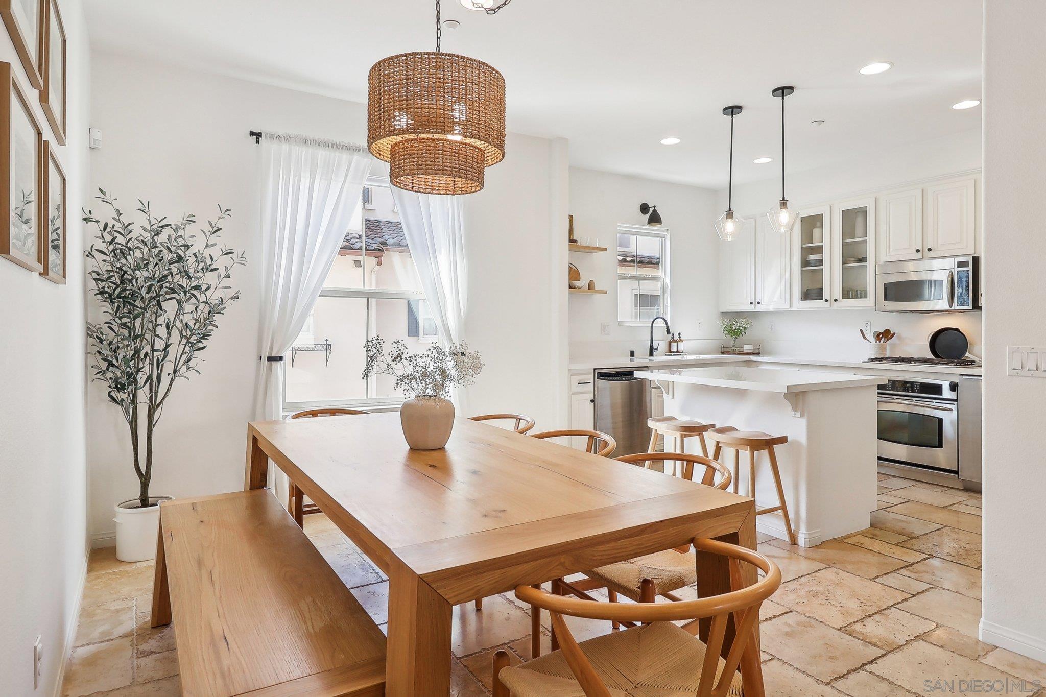 a kitchen with stainless steel appliances kitchen island granite countertop a table chairs and a refrigerator