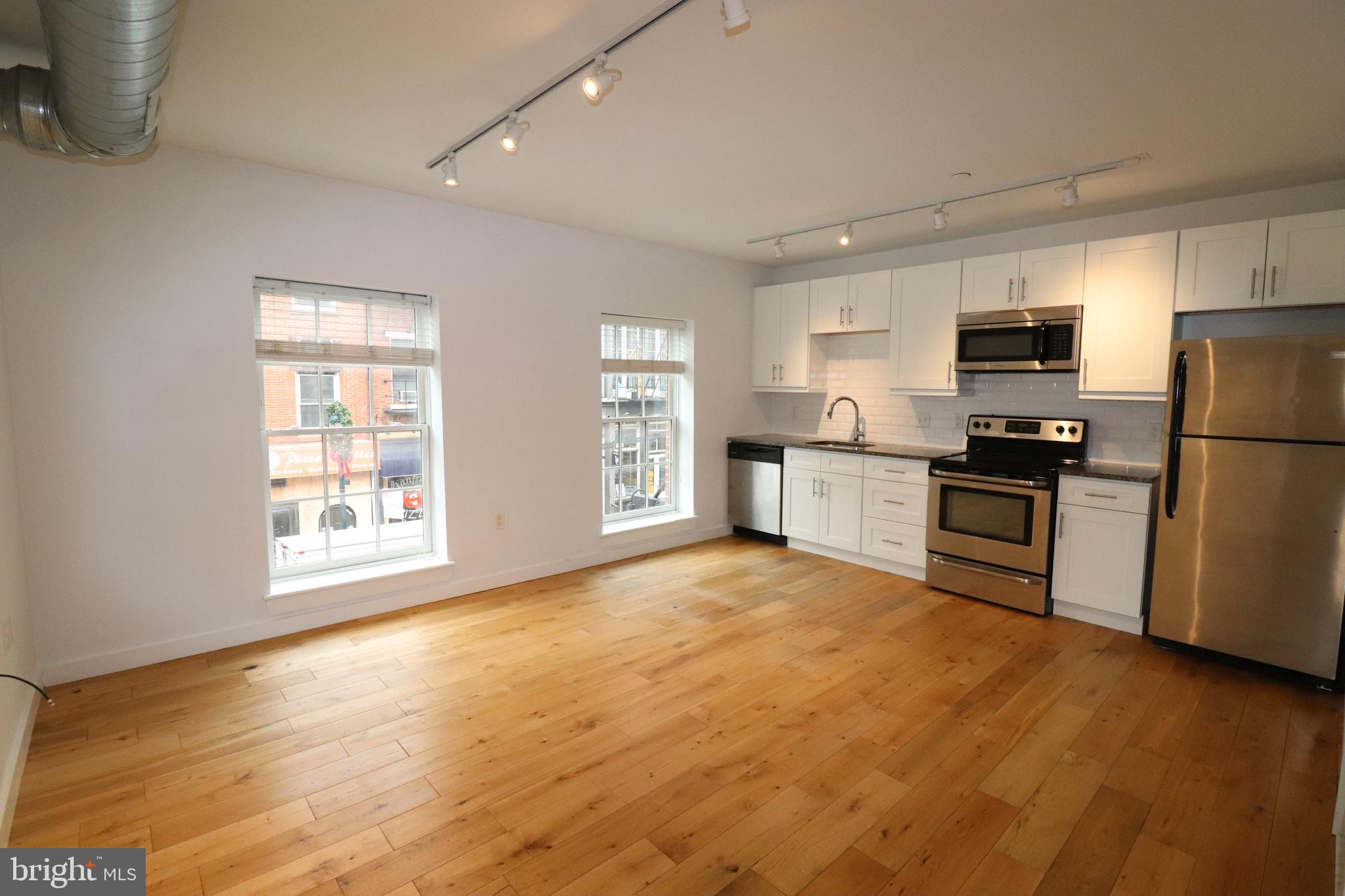 a kitchen with granite countertop a refrigerator and a stove top oven