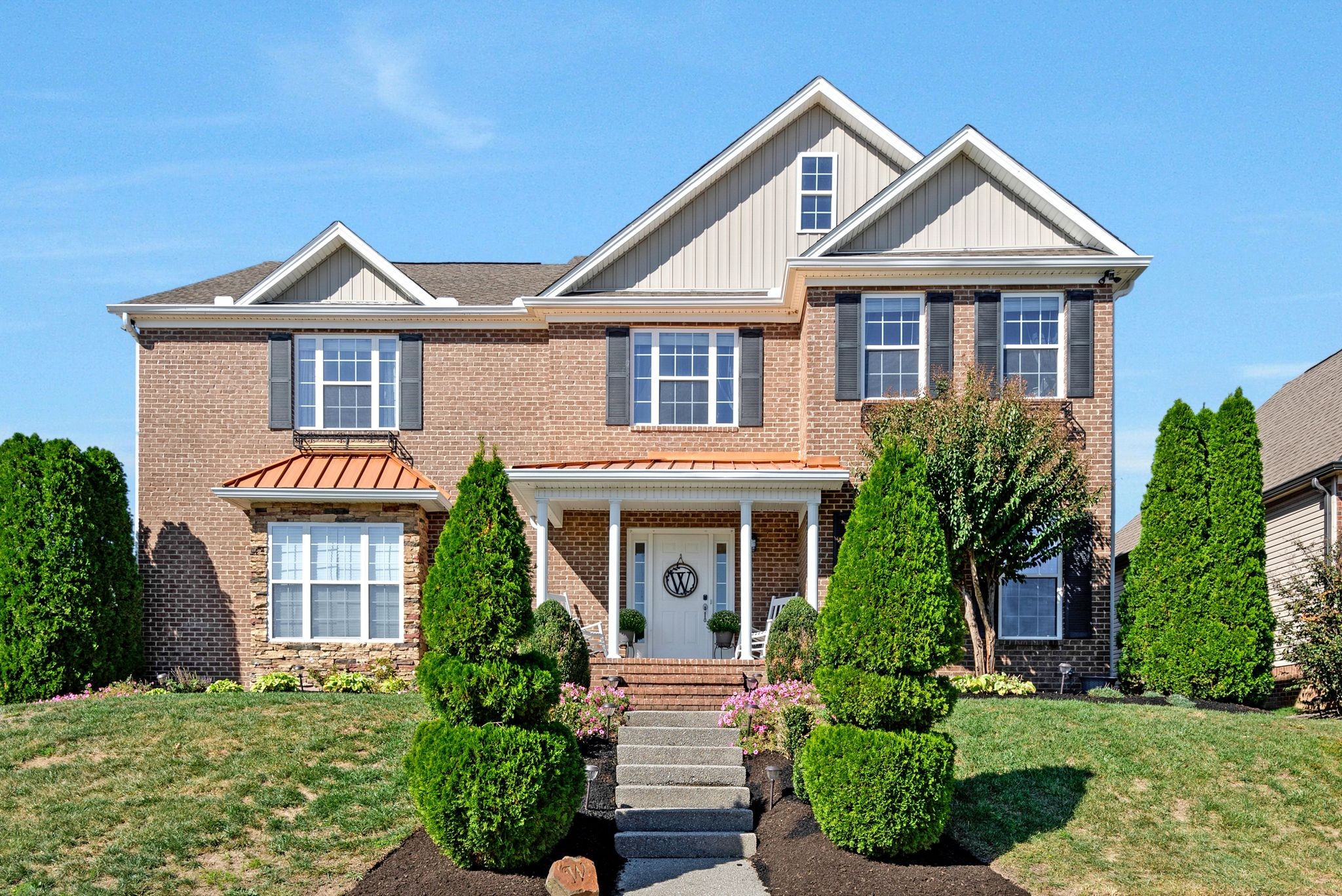 a front view of a house with yard and green space