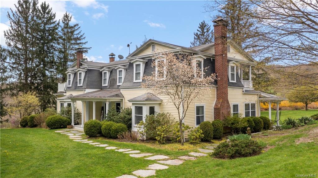 a view of a big yard in front of a brick house with large windows