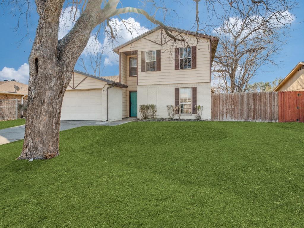 a white house that has a big yard with wooden fence