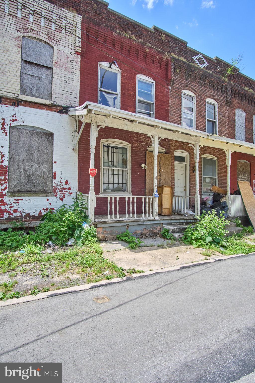 front view of a brick house with a yard and table and chairs next to a road