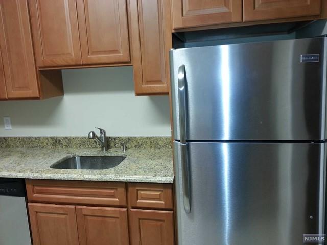 a kitchen with stainless steel appliances granite countertop a refrigerator a sink and cabinets