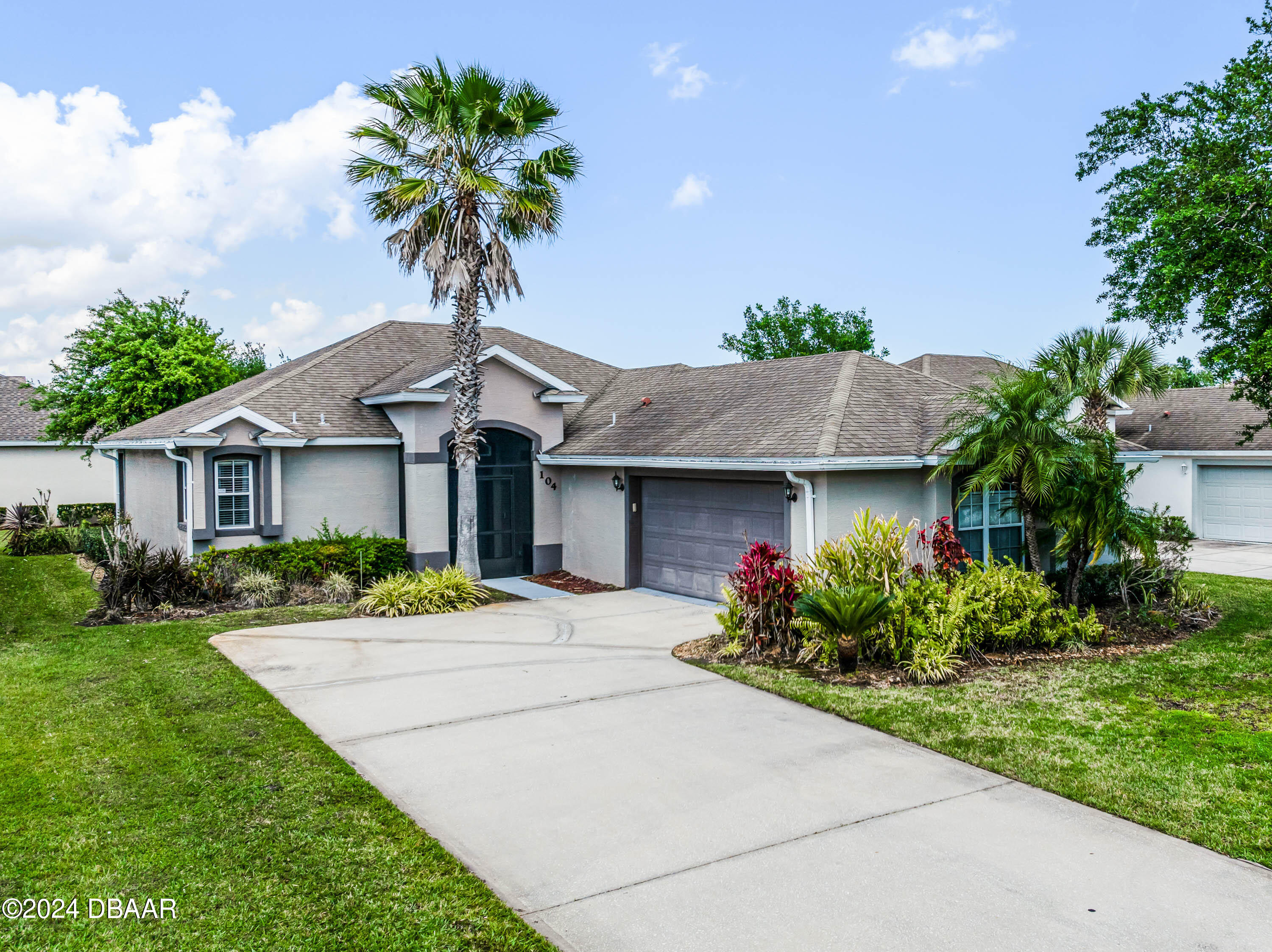 a front view of a house with a garden and palm trees