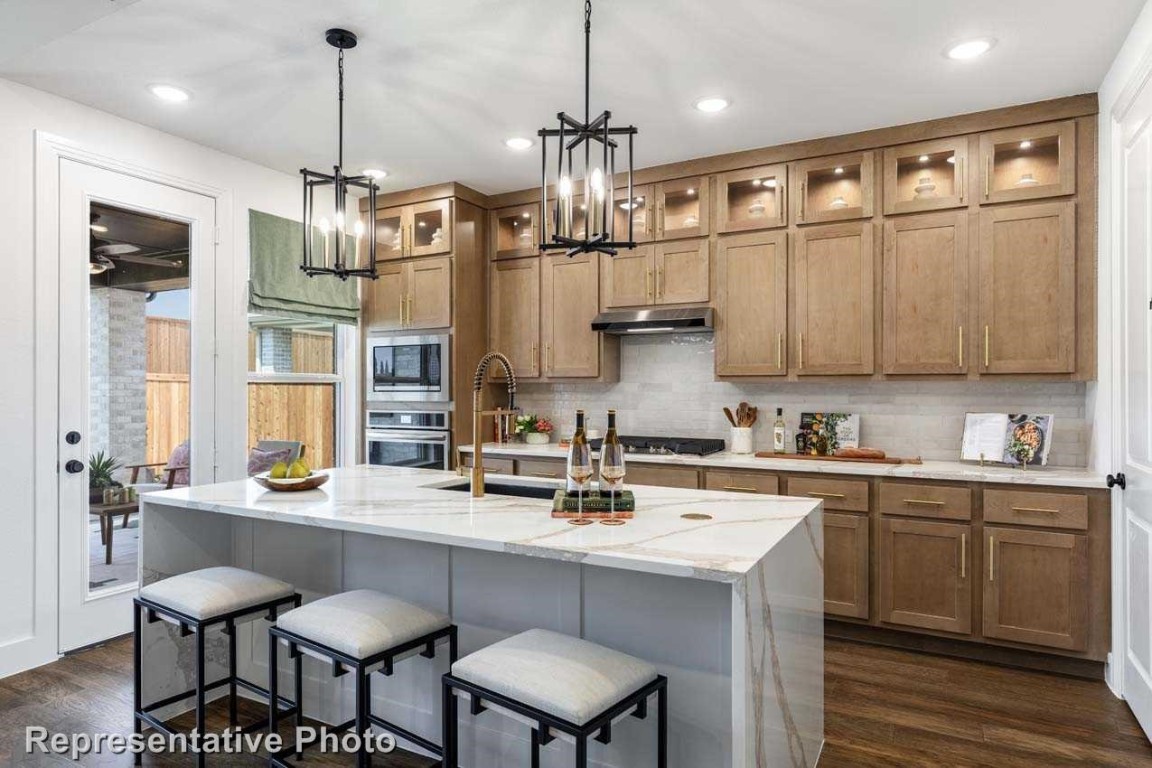 a kitchen with stainless steel appliances granite countertop a sink a stove a refrigerator and island