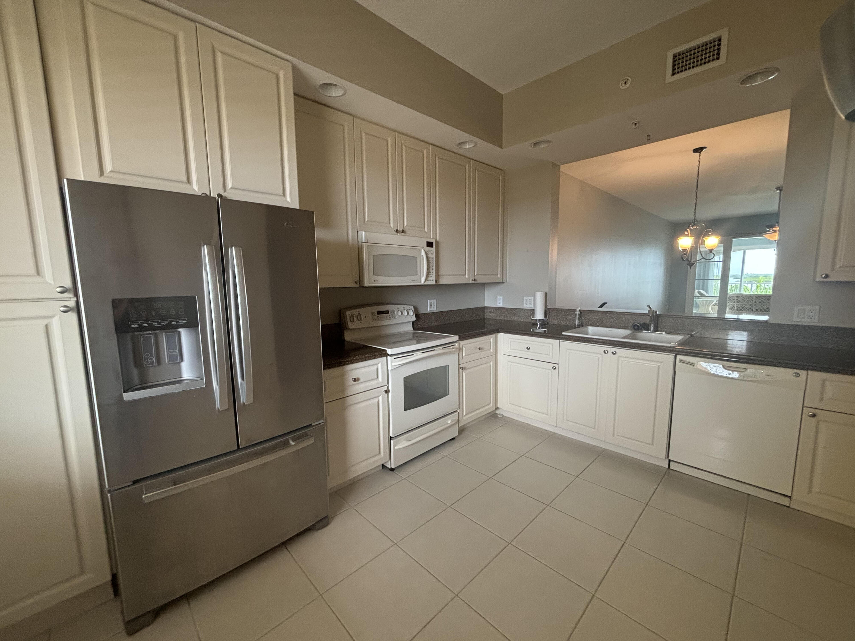 a white kitchen with granite countertop stainless steel appliances and white cabinets