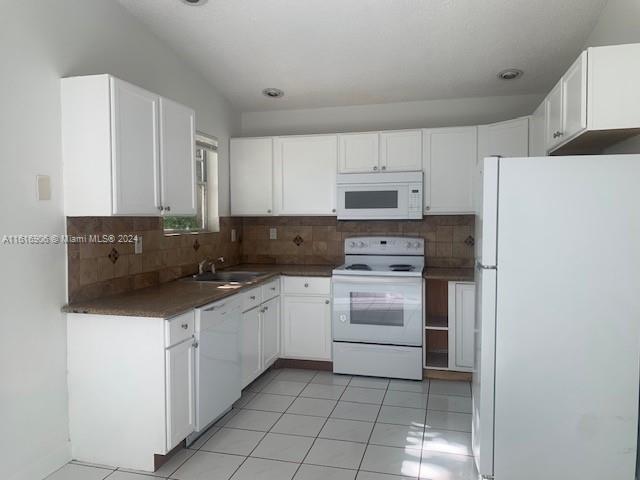 a kitchen with white cabinets and appliances