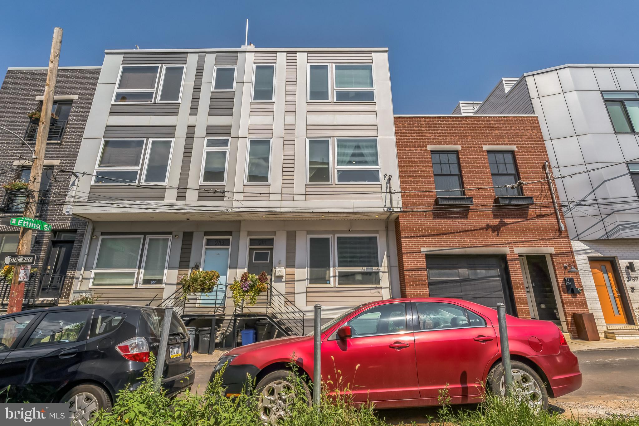 a front view of a building with lots of cars and trees