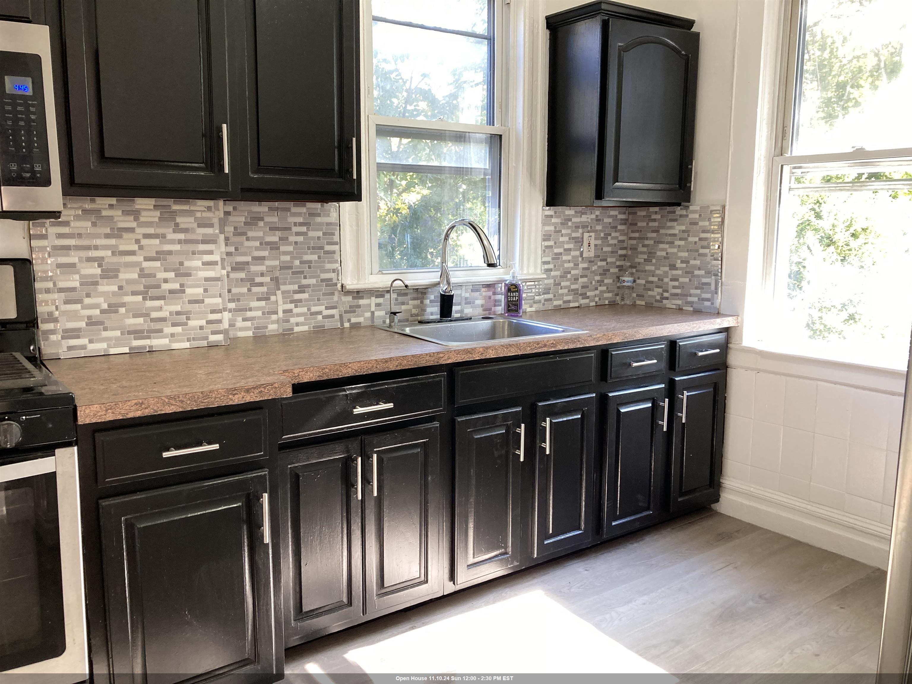 a kitchen with granite countertop stainless steel appliances a sink stove and cabinets