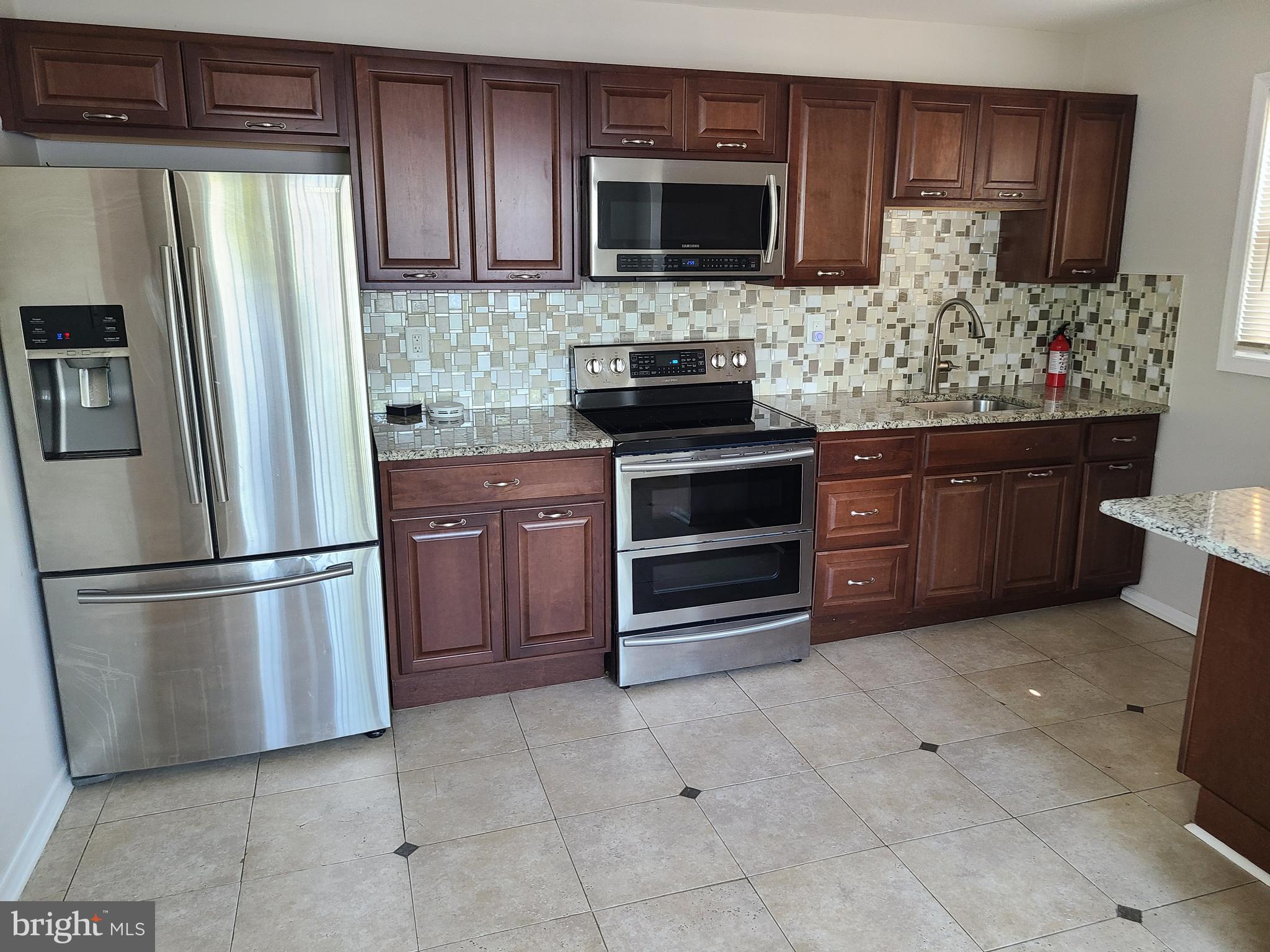 a kitchen with stainless steel appliances granite countertop a refrigerator stove and microwave