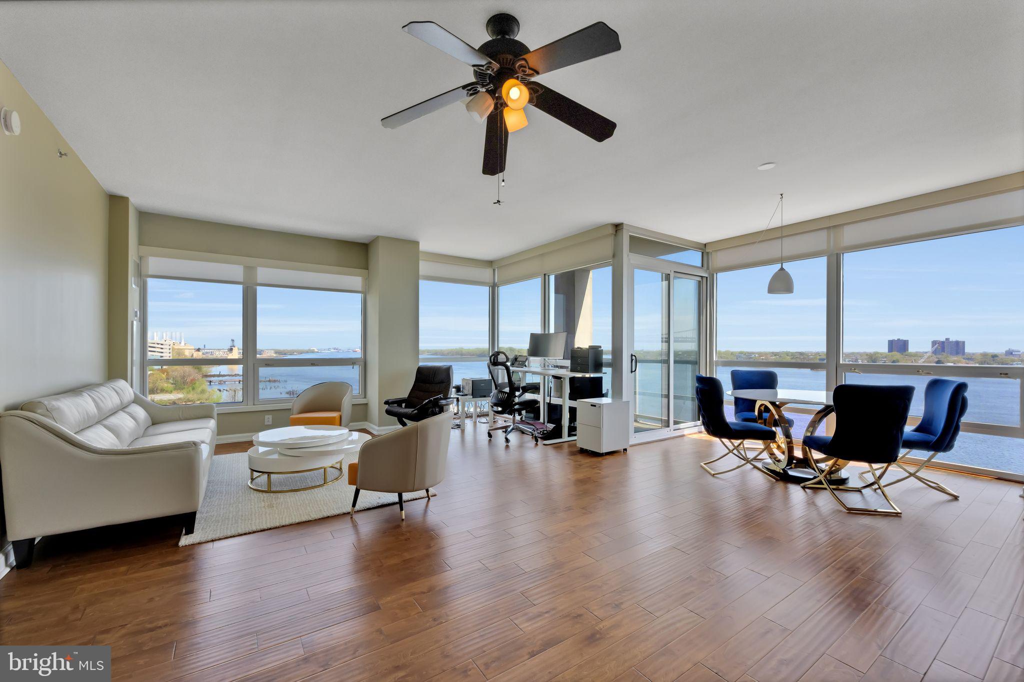 a living room with furniture floor to ceiling window and wooden floor