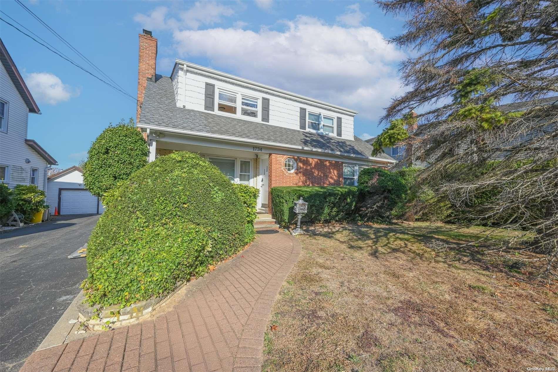 a front view of a house with a yard and plant