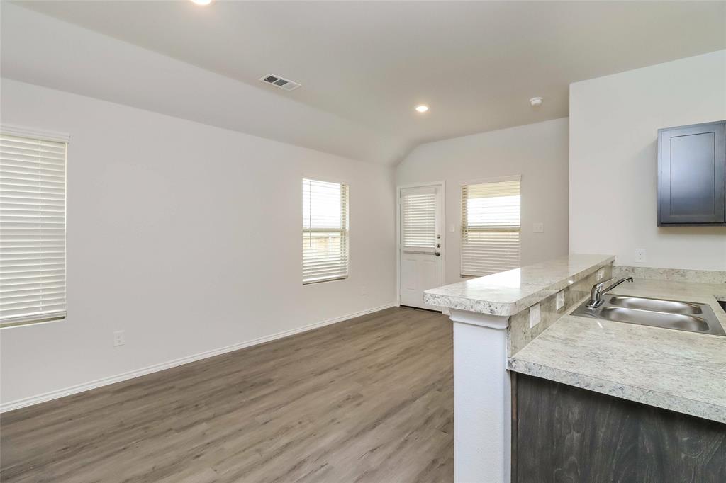 a kitchen with granite countertop kitchen island wooden floors wooden cabinets and sink