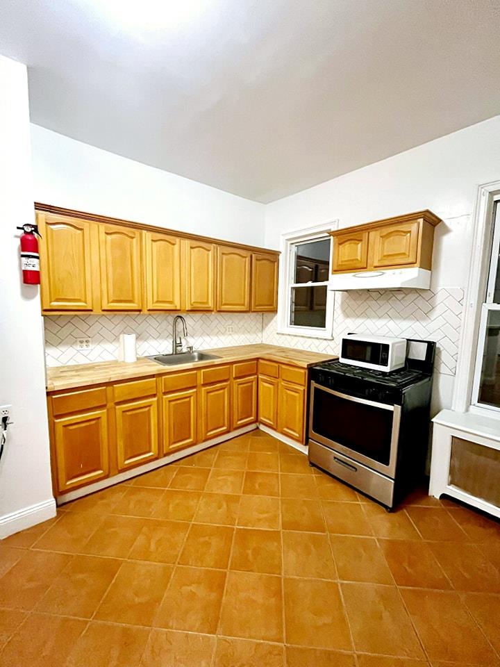 a kitchen with stainless steel appliances granite countertop a stove a sink and a microwave