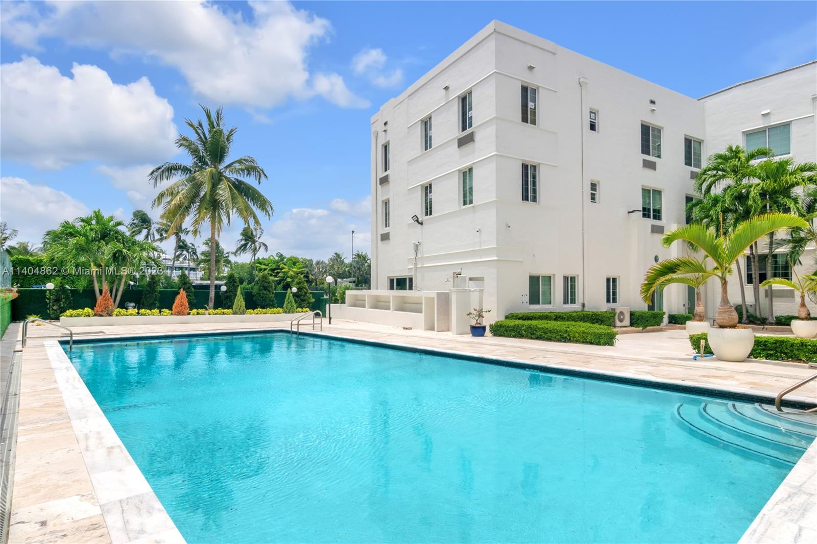 a view of a swimming pool with a lawn chairs under palm trees