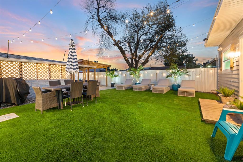 a view of a patio with table and chairs potted plants and a large tree