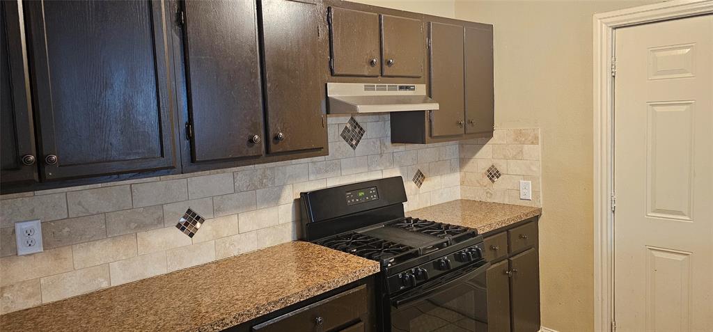 a kitchen with granite countertop a stove sink and cabinets