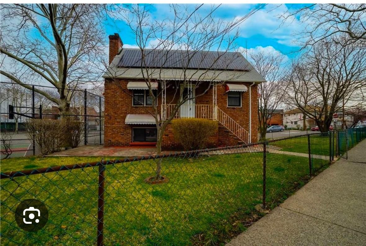 View of front facade featuring a front lawn and solar panels