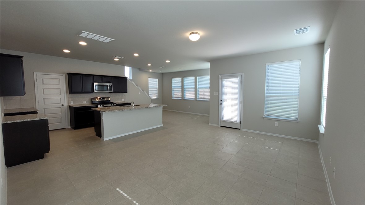 a view of kitchen with kitchen island microwave and refrigerator