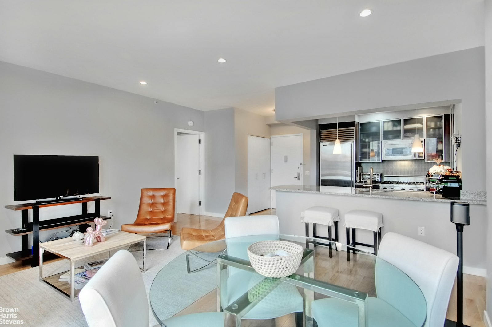 a living room with furniture a flat screen tv and kitchen view