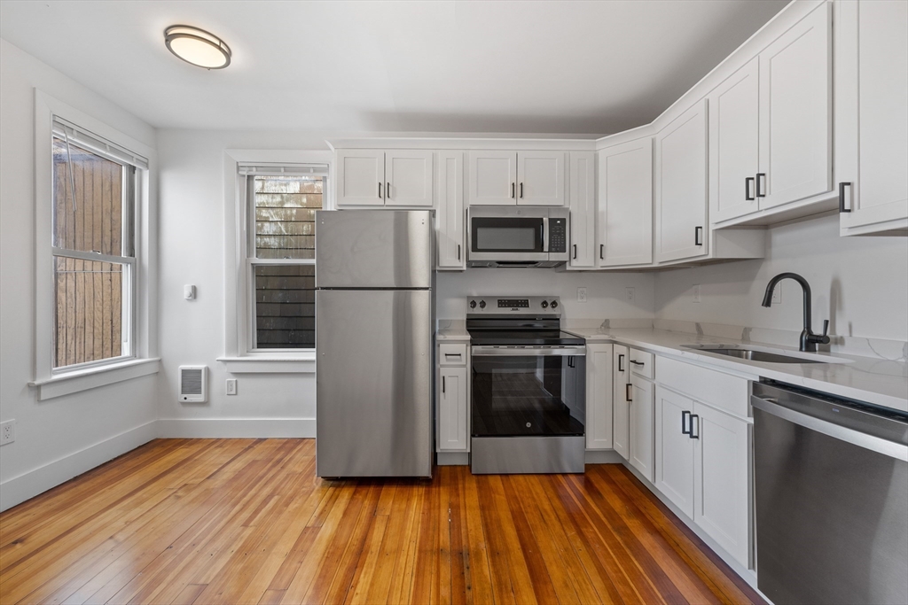 a kitchen with granite countertop a refrigerator stove and sink