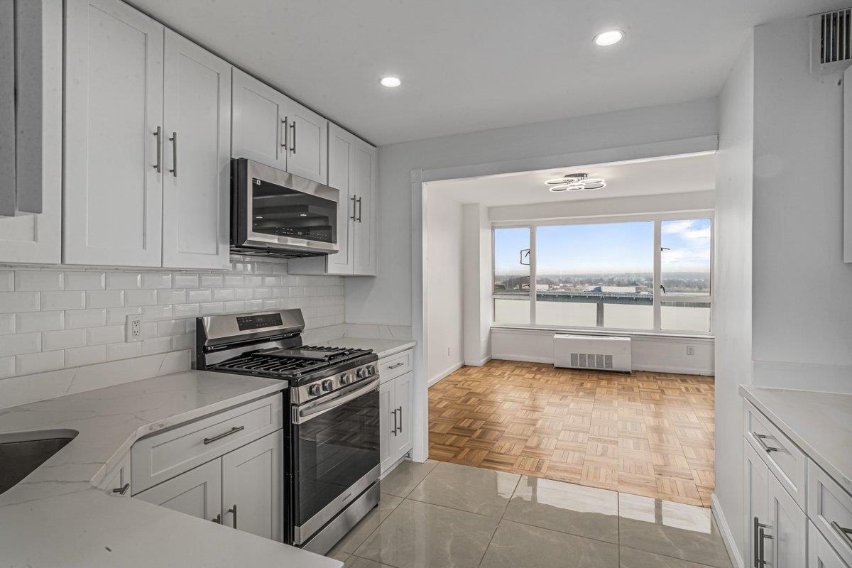 Kitchen featuring light stone countertops, white cabinetry, light tile patterned floors, and stainless steel appliances