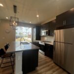 a kitchen with stainless steel appliances granite countertop a refrigerator a sink a stove and a microwave