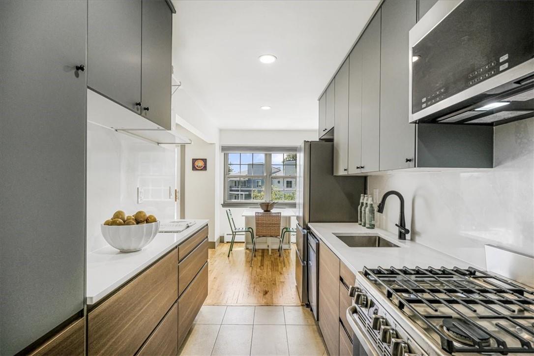 This unit's showstopper - A brand new kitchen featuring quartz countertop & backsplash, modern 2-tone cabinetry, open shelving, and stainless steel appliances.