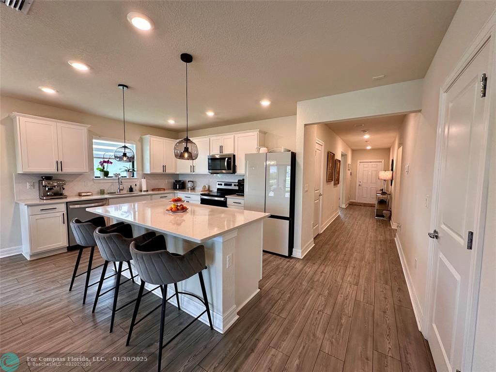 a open kitchen with stainless steel appliances granite countertop a refrigerator a sink dishwasher a stove and white countertops with wooden floor