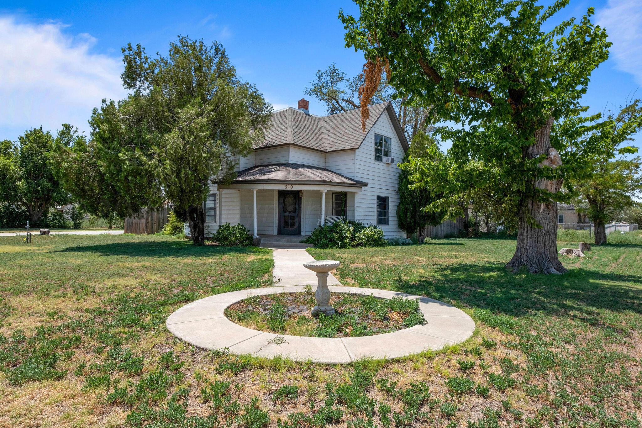 a front view of a house with a yard fountain and trees