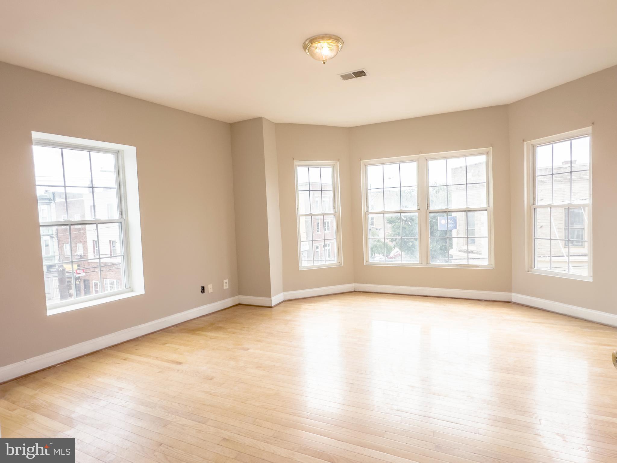 a view of an empty room with a window and wooden floor