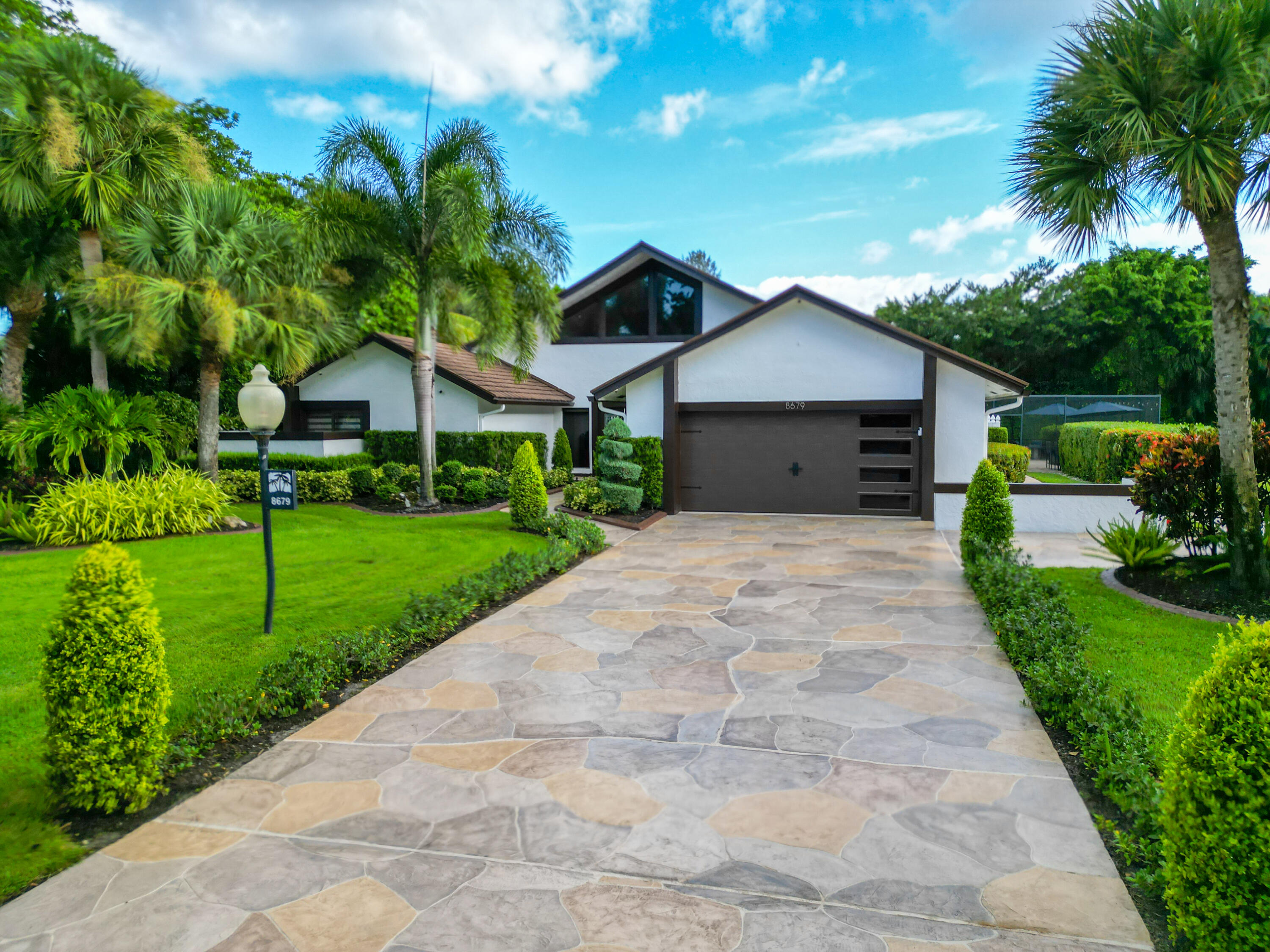 a front view of a house with a yard and potted plants