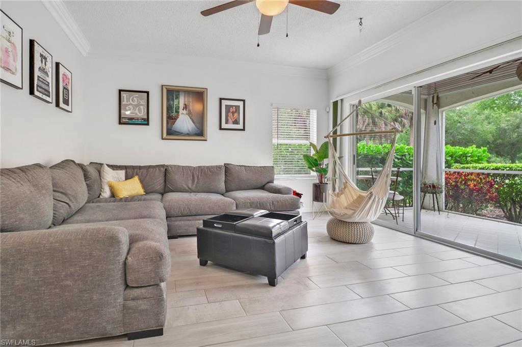 Living room with a textured ceiling, ceiling fan, and ornamental molding